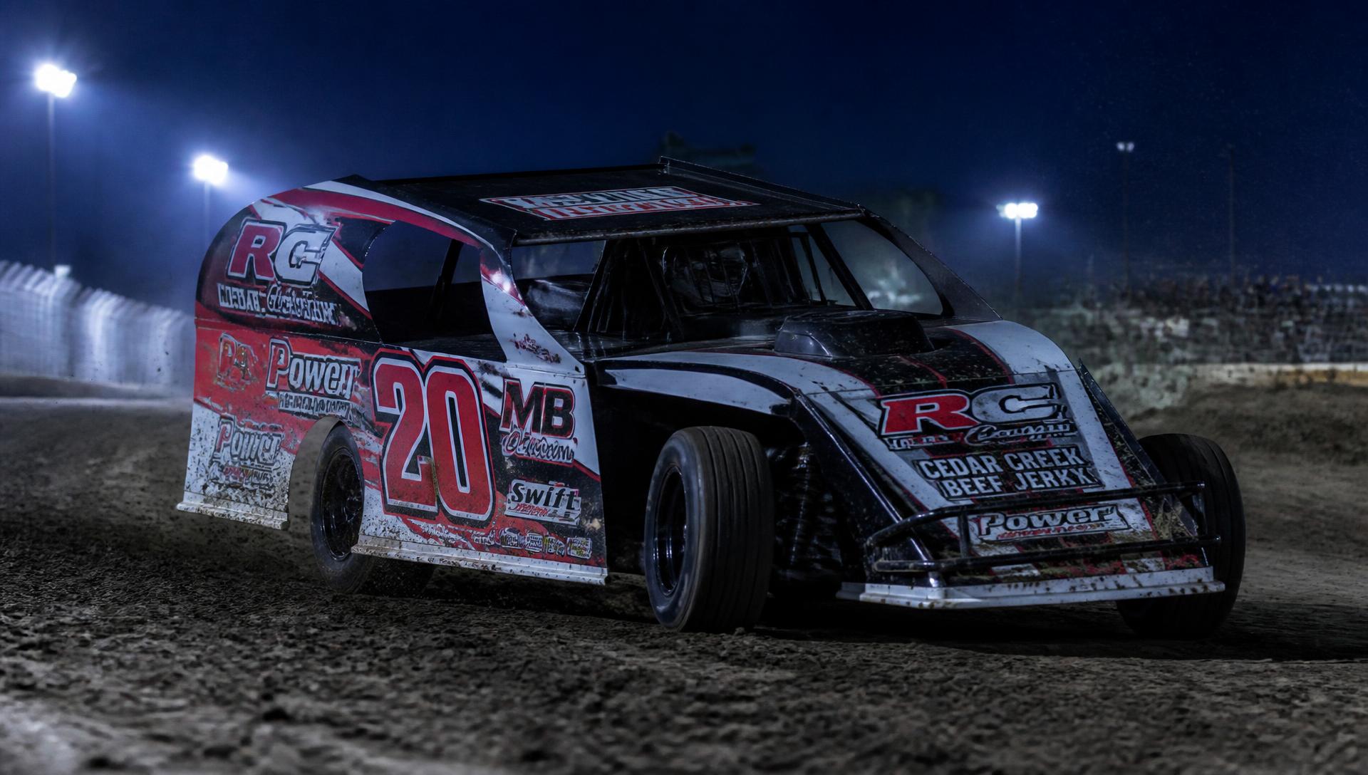 IMCA dirt modified race car with a printed vinyl wrap on a lit dirt oval at night